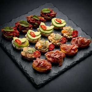 Gourmet Bruschetta Platte mit dunklem und hellem Brot, belegt mit Garnelen, Avocado und Schinken.