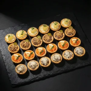 Tartelette Box mit 24 Mürbeteig-Tartelettes (ca. 1.200 g): Lachs-Tatar, Waldpilz-Julienne, Hähnchen-Pâté und Obatzda – Moment Catering Stuttgart.