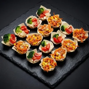 Vegetarische Wrap-Körbchen Box von Moment Catering Stuttgart mit 16 knusprig gebackenen Wrap-Körbchen: Asia-Gemüse mit Paprika, Karotte, Zwiebel und Mais sowie Hummus mit Brokkoli und Cherry-Tomaten in Zitronen-Basilikum-Marinade – ideal für Business-Events und Fingerfood-Buffet.